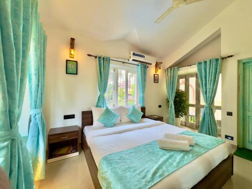 een slaapkamer met een bed met blauwe gordijnen bij Rustic Private Pool Villa # 8 by SAZJ Hospitality in Saligao