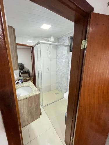 uma casa de banho com uma cabina de duche em vidro e um lavatório. em Apartamento no Centro em Porto Seguro