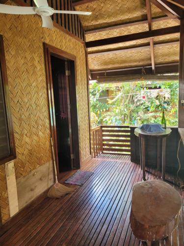 um alpendre de uma casa com uma mesa e um banco em MALAIKA RESORT em Port Barton