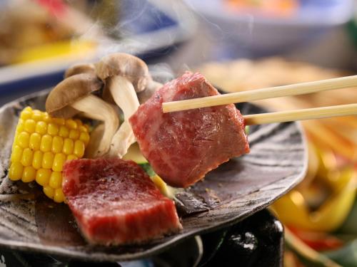un plato de comida con verduras de carne y palillos en Kamikochi Hotel en Matsumoto