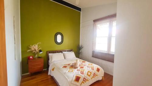 a bedroom with a bed with a green wall at Rancho Relaxo in Tewantin