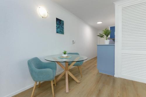 a dining room with a glass table and two chairs at 1 Bedroom @ Palm Villas #2 in Port Douglas