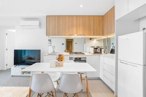 a white kitchen with a white table and chairs at Southbank Stature Building2 Bedroom Apartment in Melbourne