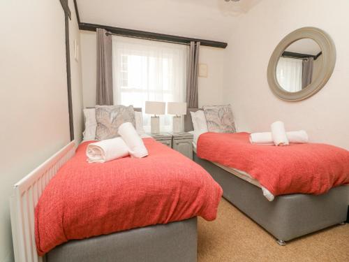 a bedroom with two beds and a mirror at Harbour Cottage in Ilfracombe