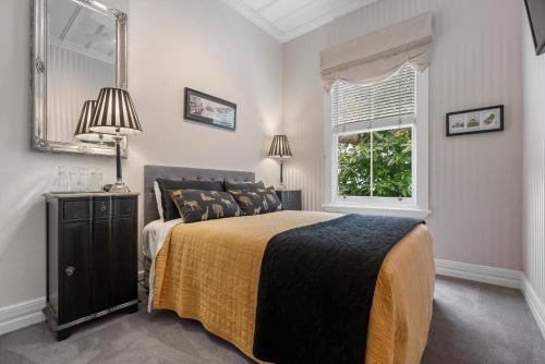 1 dormitorio con cama, ventana y espejo en Eden Park Bed And Breakfast Inn, en Auckland