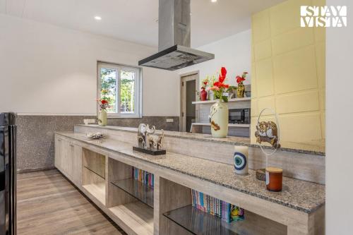 a kitchen with a long counter with books at Corbett Calling with Jacuzzi & Projector Set-Up by StayVista in Rāmnagar