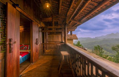 a balcony of a house with a bed and a table at Khói Panorama in Dồng Văn