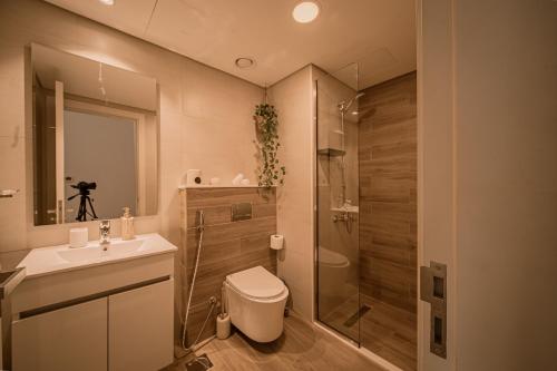 uma casa de banho com um chuveiro, um WC e um lavatório. em Raha Lofts Hosted By Voyage em Abu Dhabi