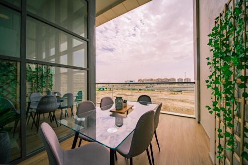 a dining room with a table and chairs and a large window at Raha Lofts Hosted By Voyage in Abu Dhabi