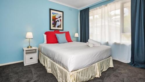 a blue bedroom with a large bed with red pillows at Ocean Blue Haven Beachside 2-Bed Unit in Hampton in Melbourne