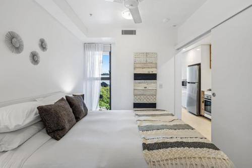 a white bedroom with a large bed with pillows at Stellar Location With Parking Pool & Gym Access in Brisbane
