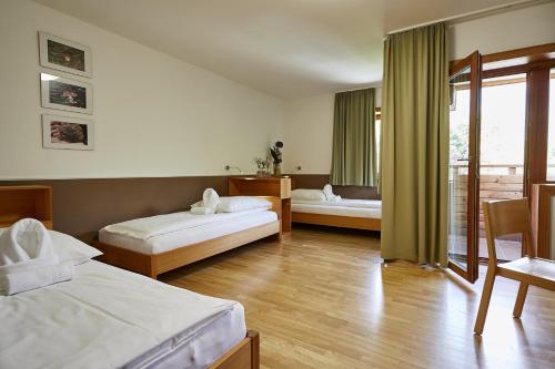 a hotel room with two beds and a balcony at FAST Ossiach in Ossiach