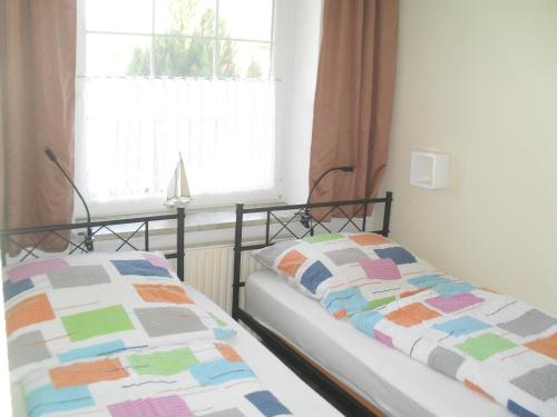 2 łóżka pojedyncze w pokoju z oknem w obiekcie Haus Rosi w mieście Friedrichskoog-Spitz