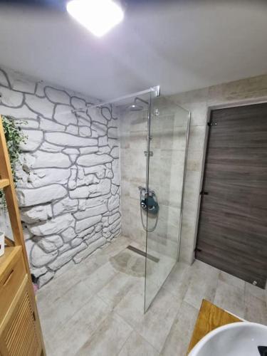 a bathroom with a shower with a stone wall at Vila Kyra in Rtina