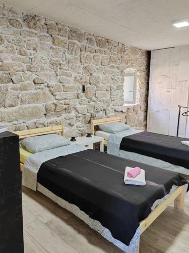 a bedroom with two beds and a stone wall at Vila Kyra in Rtina