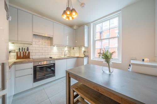 a kitchen with white cabinets and a table with a vase on it at Charming 2 Bedroom Flat in Central London in London
