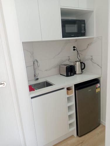 una pequeña cocina con fregadero y microondas en 11A Addison street home stay, en Auckland