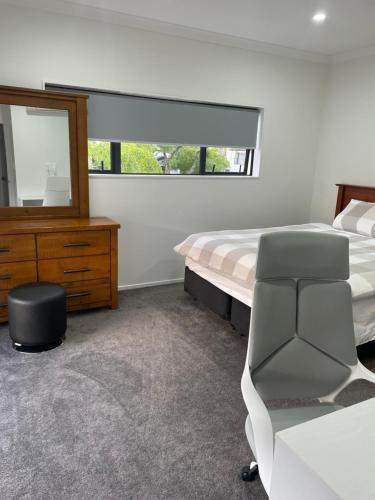 1 dormitorio con cama, espejo y silla en 11A Addison street home stay, en Auckland