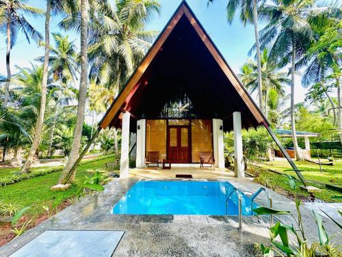 une petite maison avec une piscine en face de celle-ci dans l'établissement Elegant Hamlets Home Stay, à Chilaw