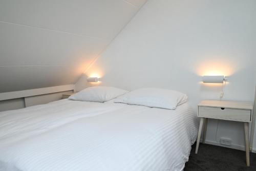 um quarto com uma cama branca e duas mesas de cabeceira em Sincfal 10 Cadzand em Cadzand-Bad