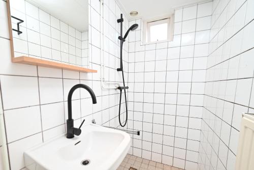 um chuveiro numa casa de banho com azulejos brancos e um lavatório. em Sincfal 10 Cadzand em Cadzand-Bad