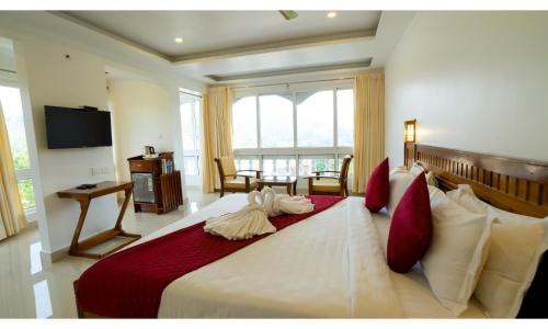 a bedroom with a large white bed with red pillows at Carmel Top Munnar in Munnar