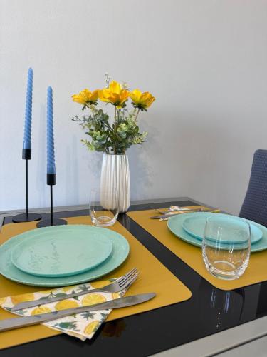 a table with two plates and a vase with yellow flowers at FK Maison in Agrinio