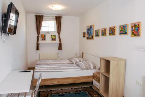 a bedroom with a bed and a desk and a tv at Budget dbl Studio free breakfast in Ljubljana