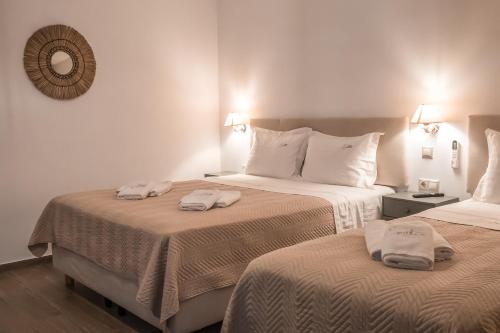 two beds in a hotel room with towels on them at Epithea Suites Kythnos 5 με ιδιωτική πισίνα in Kithnos