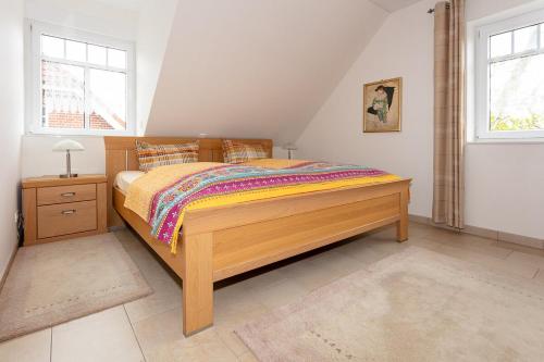 1 Schlafzimmer mit einem Holzbett und 2 Fenstern in der Unterkunft Ferienhaus Inselliebe in Borkum