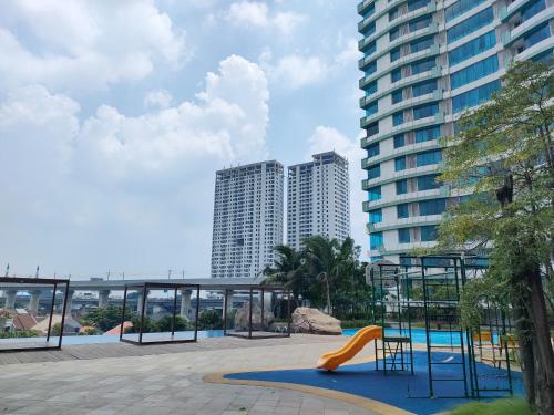 een speeltuin met een glijbaan voor hoge gebouwen bij Apartemen Grand Kamala Lagoon by Abel Stay Luxury in Pekayon Satu