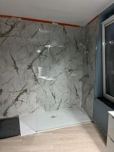 uma casa de banho com um chuveiro e uma parede em mármore. em Chambre 2 lits simples em Bruxelas