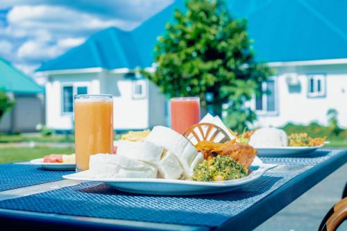 a table with plates of food and two glasses of beer at Teranga Lodge and Restaurant in Ihumwa