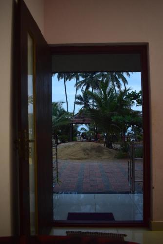 an open door with a view of a palm tree at WHITE SAND BEACH STAY- Delta hospitality- in Udupi