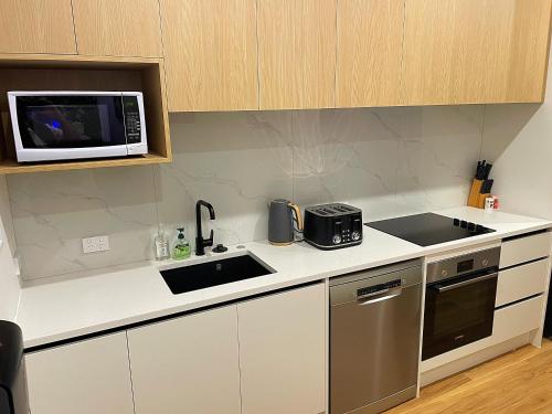 a kitchen with a sink and a microwave at Flat Bush Holiday Accomodation in Auckland