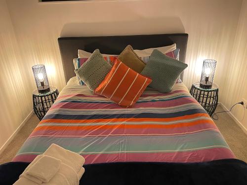 a bed with colorful pillows on it with two lamps at Flat Bush Holiday Accomodation in Auckland