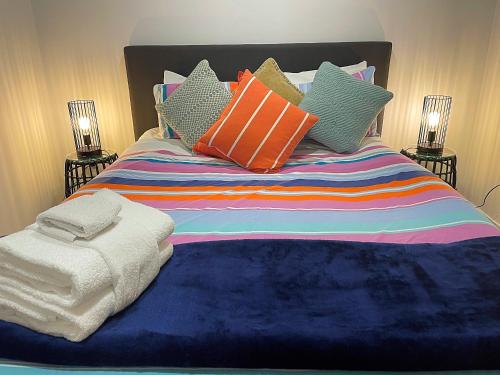 a bed with colorful pillows on top of it at Flat Bush Holiday Accomodation in Auckland