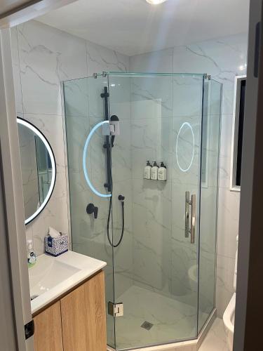 a bathroom with a glass shower with a sink at Flat Bush Holiday Accomodation in Auckland