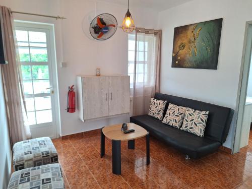 a living room with a black couch and a table at Le Beau Manguier Residence Bed & Breakfast in Pereybere