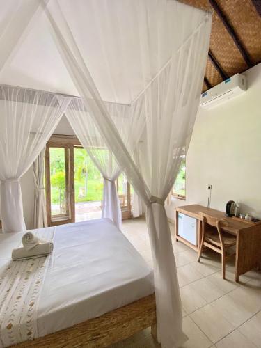 - une chambre avec un lit à baldaquin blanc et un bureau en bois dans l'établissement Green Coco House, à Amed