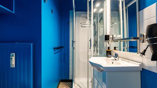 La salle de bains bleue est pourvue d'un lavabo et d'une douche. dans l'établissement L Appart de Lilou : Paisible / Confort /Proche Centre Ville, à Dijon