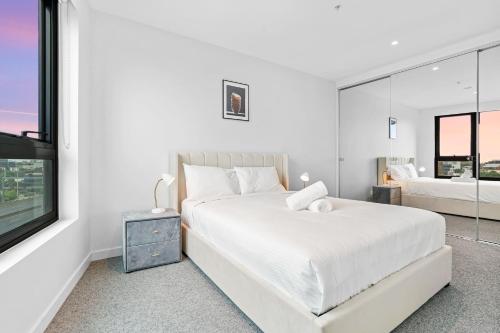 a white bedroom with a large bed and a window at Southbank Stature Building2 Bedroom Apartment in Melbourne