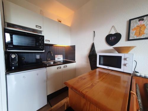 Il comprend une cuisine équipée d'un four micro-ondes et d'un comptoir en bois. dans l'établissement Résidence Le Cairn - Agréable studio 4 personnes au coeur des Orres MAE-6471, aux Orres