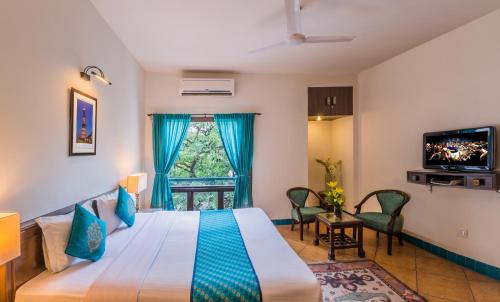ein Hotelzimmer mit einem Bett und einem TV in der Unterkunft Home@F37 Kailash Colony Metro in Neu-Delhi