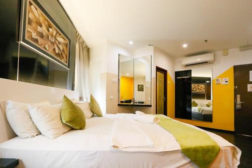 ein großes weißes Bett in einem Zimmer mit Spiegel in der Unterkunft Golden Roof Hotel Ampang Ipoh in Ipoh