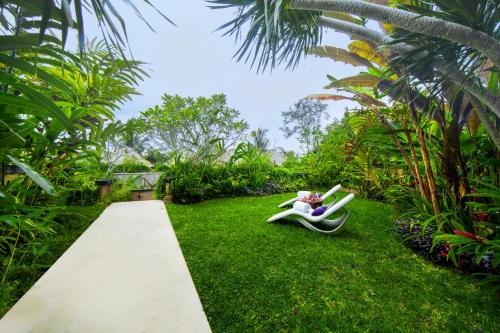 a person sitting on a lawn chair in the grass at Nandini Jungle by Hanging Gardens in Payangan