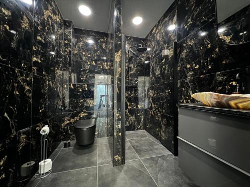 een badkamer met een douche en zwarte marmeren muren bij Mieterlux Frankfurt Heusenstamm 46 in Heusenstamm
