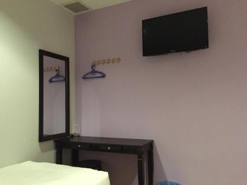 um quarto com uma televisão na parede e uma mesa em Tas Sakura Budget Hotel em Kampong Baharu