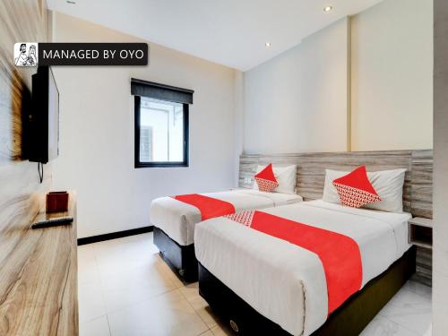 una camera con due letti con lenzuola rosse e bianche di Super OYO Flagship 90775 I Sleep Hotel Bandung a Bandung