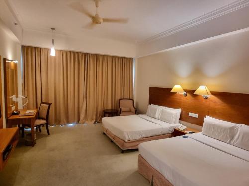 a hotel room with two beds and a desk at Heritage Hotel Cameron Highlands in Cameron Highlands
